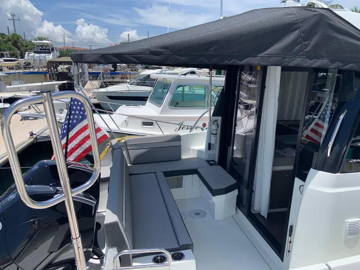  Yacht Photos Pics 2025 Jeanneau NC 1095 Coupe boat with seating area and American flag in marina.