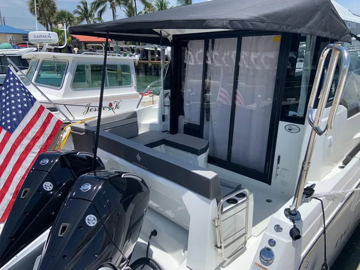  Yacht Photos Pics 2025 Jeanneau NC 1095 Coupe boat with American flag, docked near palm trees.