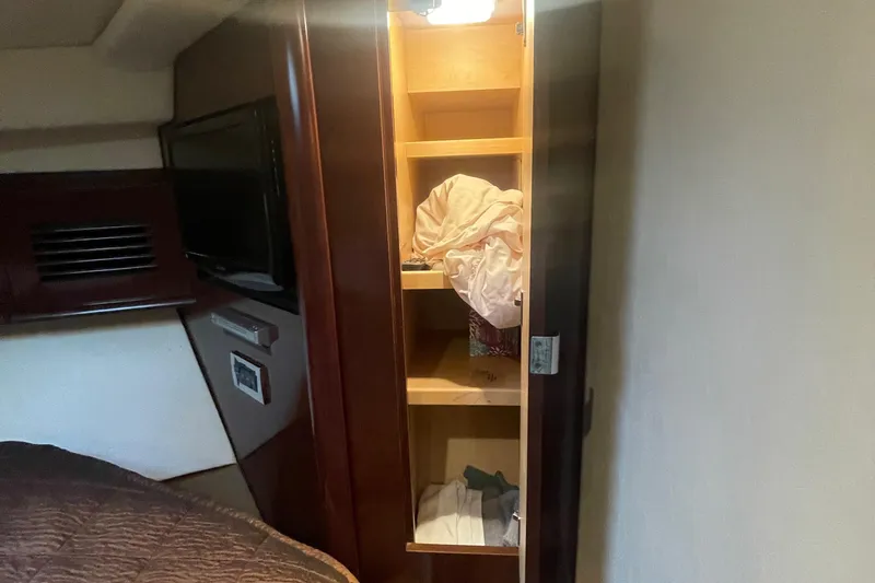 Maddie Janes Yacht Photos Pics 2009 Sea Ray 40 Sundancer interior with open wooden cabinet and bedding.