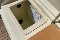 Open storage compartment on 2023 Invictus GT280 boat, featuring wooden and metal finishes.