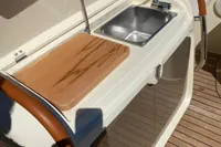 2023 Invictus GT280 yacht kitchenette with sink and cutting board on teak deck.