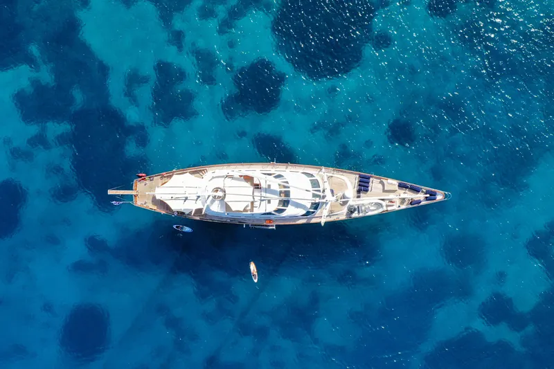 Tamarita Yacht Photos Pics Aerial view of 1992 Perini Navi 46 yacht on clear blue ocean water.