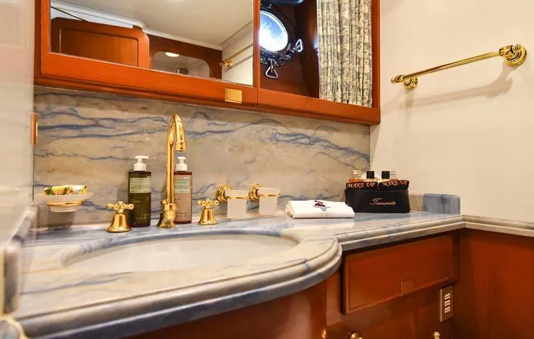 Tamarita Yacht Photos Pics Luxurious yacht bathroom with marble countertop, gold fixtures, and elegant toiletries on Perini Navi 46, 1992.