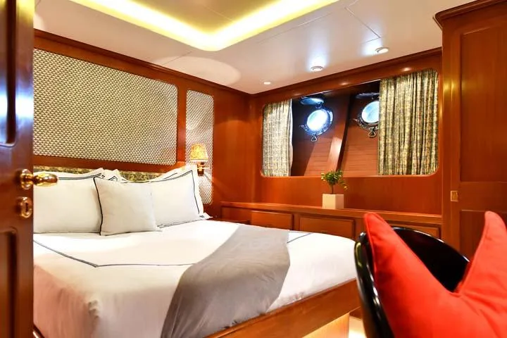 Tamarita Yacht Photos Pics Luxurious cabin interior of 1992 Perini Navi 46 yacht with elegant wood paneling and cozy bedding.