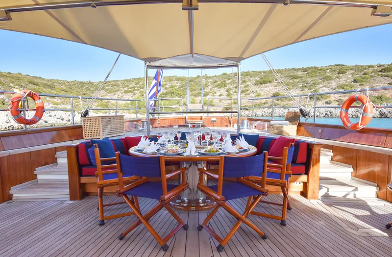 Tamarita Yacht Photos Pics Luxurious dining setup on 1992 Perini Navi 46 yacht deck, with scenic coastal view.