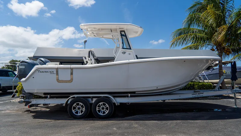  Yacht Photos Pics 2025 Tidewater 256 LXF boat on trailer, parked outdoors under blue sky.