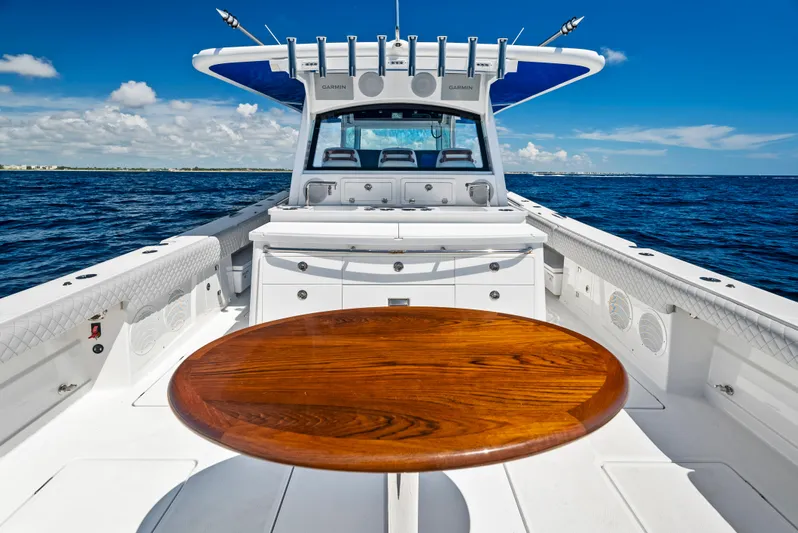 Strong III Yacht Photos Pics 2022 HCB Suenos boat with wooden table, cruising on open sea under clear blue sky.