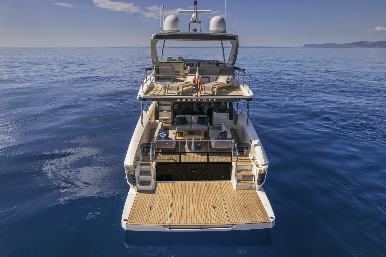 2025 Absolute 60 Fly Co Ownership yacht on calm ocean waters, rear view.