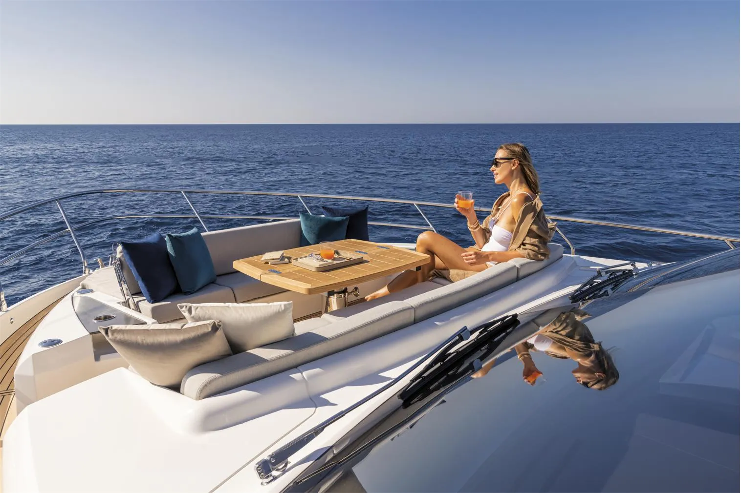 Woman relaxing on 2025 Absolute 60 Fly Co Ownership yacht, enjoying a drink at sea.