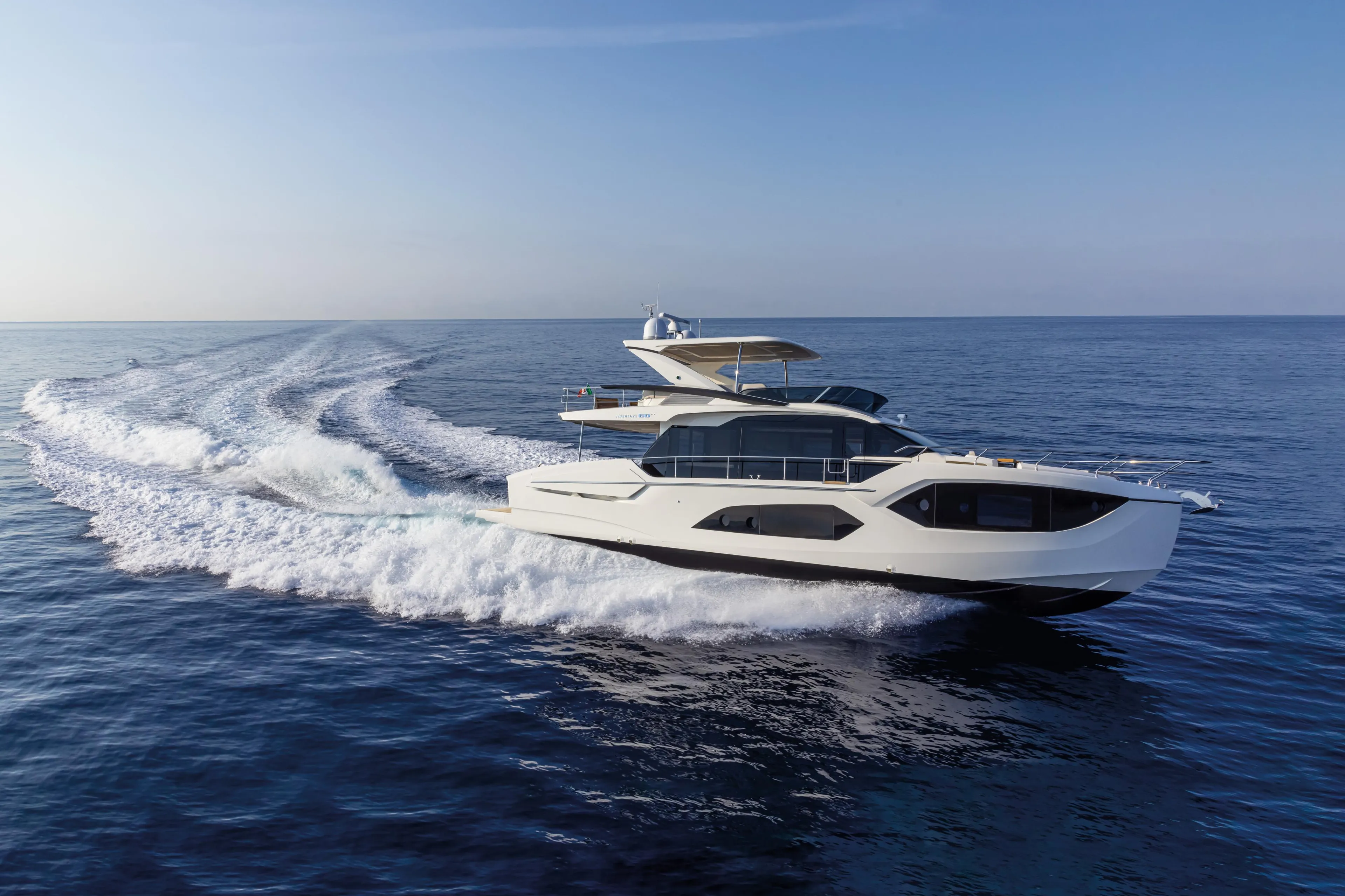 2025 Absolute 60 Fly Co Ownership yacht cruising on open sea under clear blue sky.