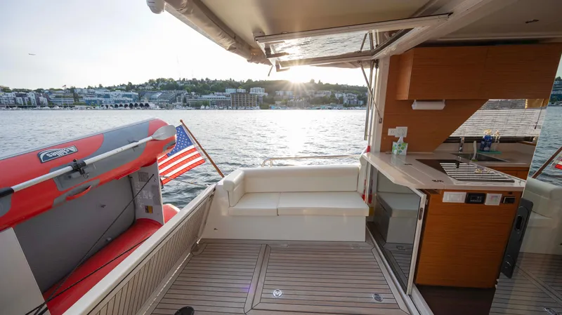 Pastiche Yacht Photos Pics 2019 Greenline Hybrid boat interior with kitchen, seating, and American flag on a sunny day.