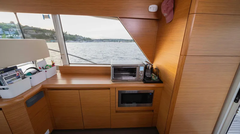 Pastiche Yacht Photos Pics Interior of 2019 Greenline Hybrid yacht with wooden cabinetry and appliances, overlooking water.