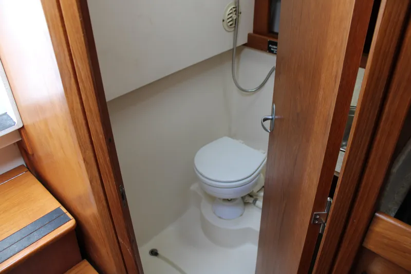 Irish Luck Yacht Photos Pics 2002 Mainship Pilot 34 boat bathroom with wooden door and compact toilet.