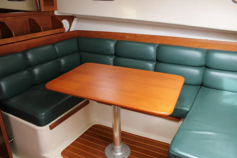 Irish Luck Yacht Photos Pics 2002 Mainship Pilot 34 interior with green cushioned seating and wooden table.