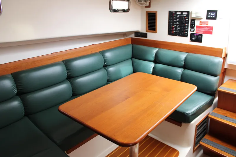 Irish Luck Yacht Photos Pics 2002 Mainship Pilot 34 interior with green cushioned seating and wooden table.