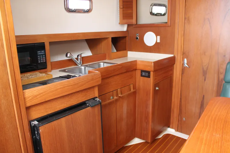 Irish Luck Yacht Photos Pics 2002 Mainship Pilot 34 interior galley with wood cabinetry, sink, and appliances.
