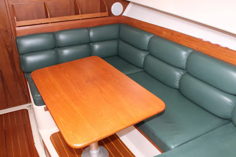Irish Luck Yacht Photos Pics 2002 Mainship Pilot 34 interior with green leather seating and wooden table.