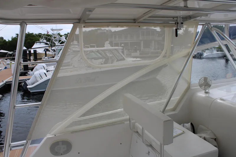 Irish Luck Yacht Photos Pics 2002 Mainship Pilot 34 interior view with marina backdrop, featuring seating and clear enclosure.