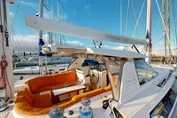 Luxurious 2012 Amel 64 yacht with orange seating, docked in a marina under clear blue skies.