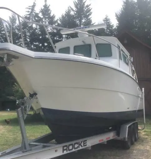 Rampage Yacht Photos Pics 2001 Rampage 30 Express boat on trailer, surrounded by trees and a wooden building.