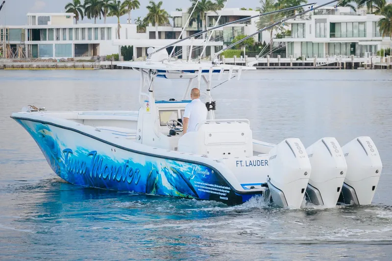  Yacht Photos Pics 2007 Yellowfin 36 Offshore boat with vibrant graphics, cruising near modern waterfront homes.