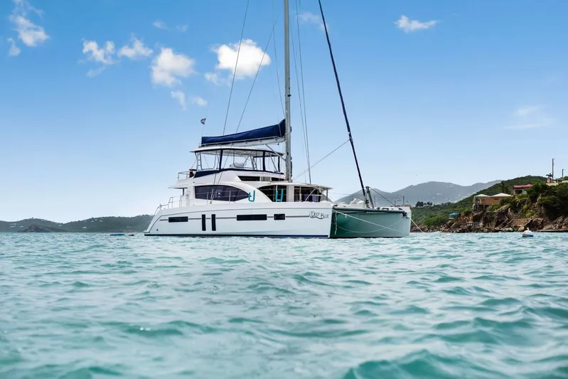 Deep Blue Yacht Photos Pics 2016 Leopard 58 Catamaran sailing in clear blue waters near a scenic coastline.