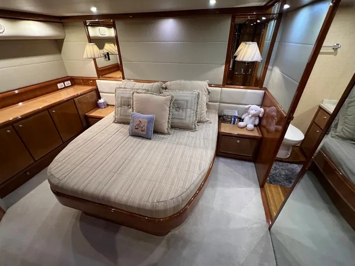  Yacht Photos Pics Luxurious bedroom interior of a 2004 Bertram 670 yacht with cozy bed and elegant decor.