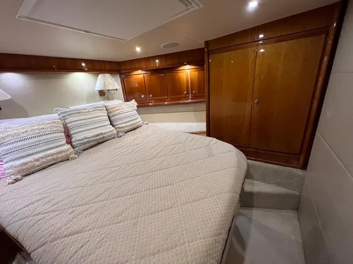  Yacht Photos Pics Luxurious bedroom interior of a 2004 Bertram 670 yacht with wooden cabinets and cozy bedding.