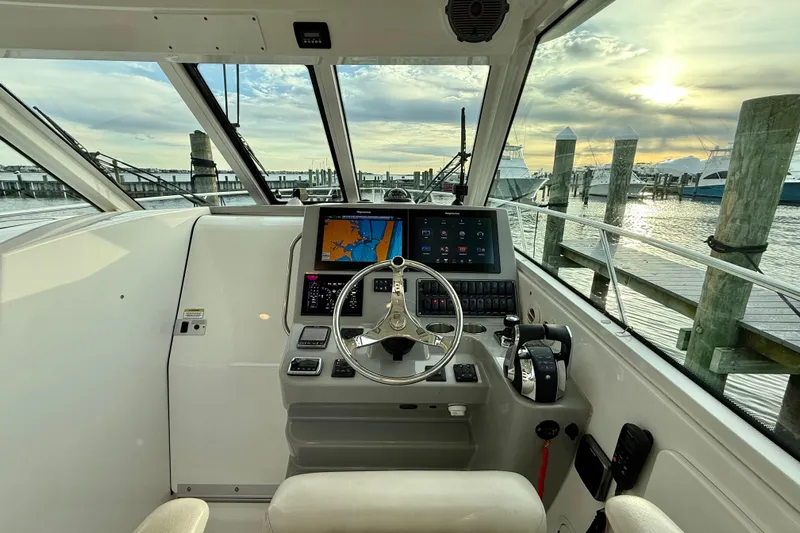  Yacht Photos Pics Pilothouse interior of 2014 Boston Whaler 345 Conquest, featuring navigation controls and marina view.