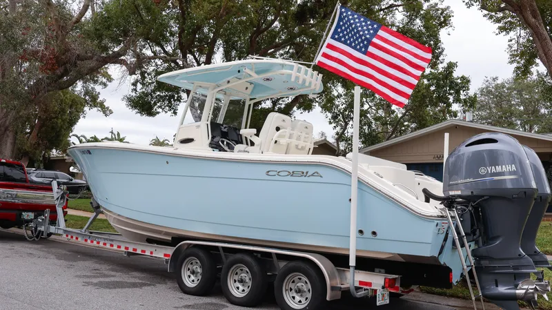  Yacht Photos Pics 2023 Cobia 280 Center Console boat on trailer with American flag and Yamaha engine.