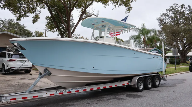  Yacht Photos Pics 2023 Cobia 280 Center Console boat on a trailer, light blue hull, parked on a street.