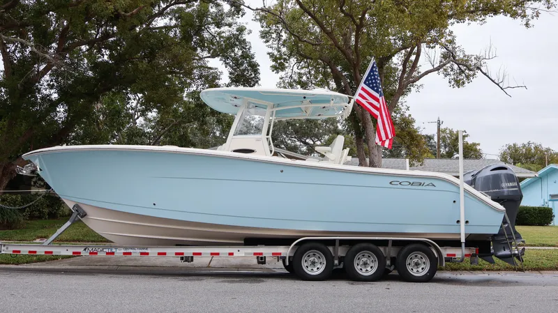  Yacht Photos Pics 2023 Cobia 280 Center Console boat on trailer with American flag.