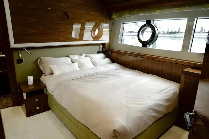  Yacht Photos Pics Luxurious bedroom interior of 2018 Sunseeker 95 yacht with elegant bedding and porthole window.