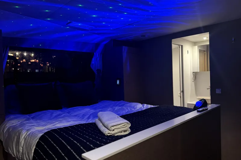 Who Cares Yacht Photos Pics Luxurious NEEL 51 yacht bedroom with ambient blue lighting, modern design, and cozy bedding.