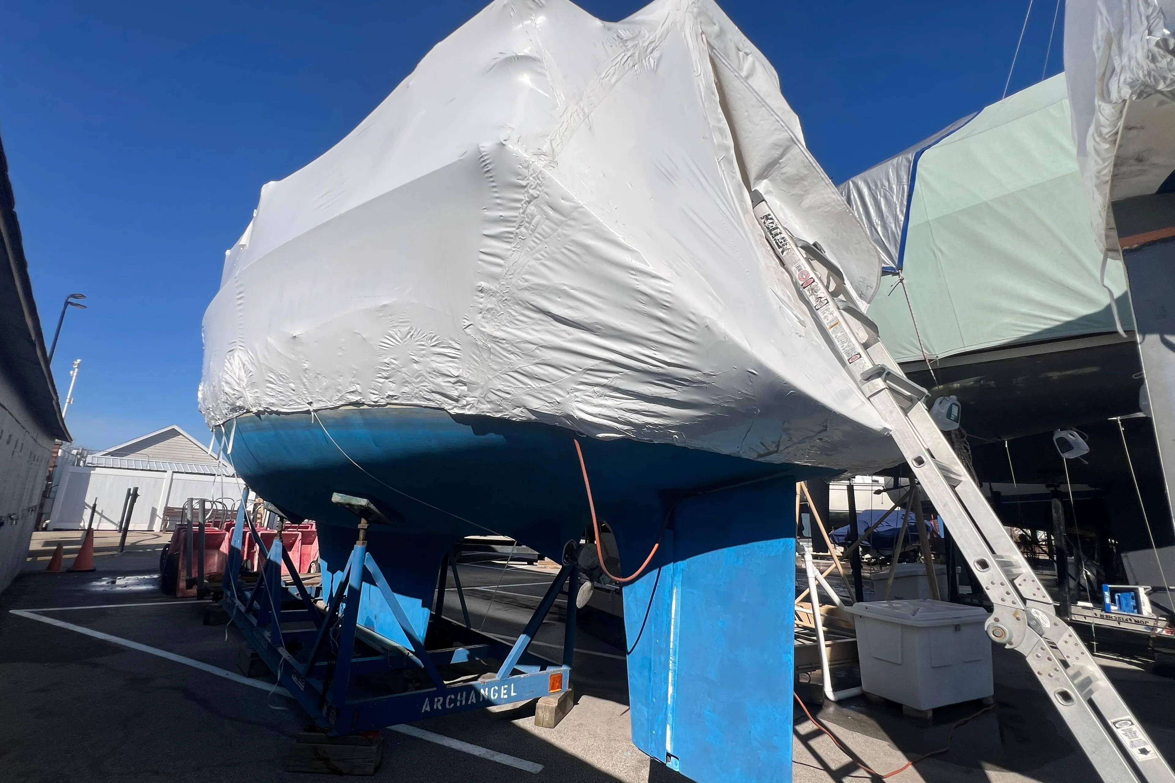1996 Caliber 35 LRC sailboat covered and elevated on a stand in a boatyard.