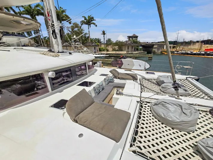 Cool Runnings IV Yacht Photos Pics Lagoon 560 S2 catamaran deck with seating and netting, docked in a tropical marina.