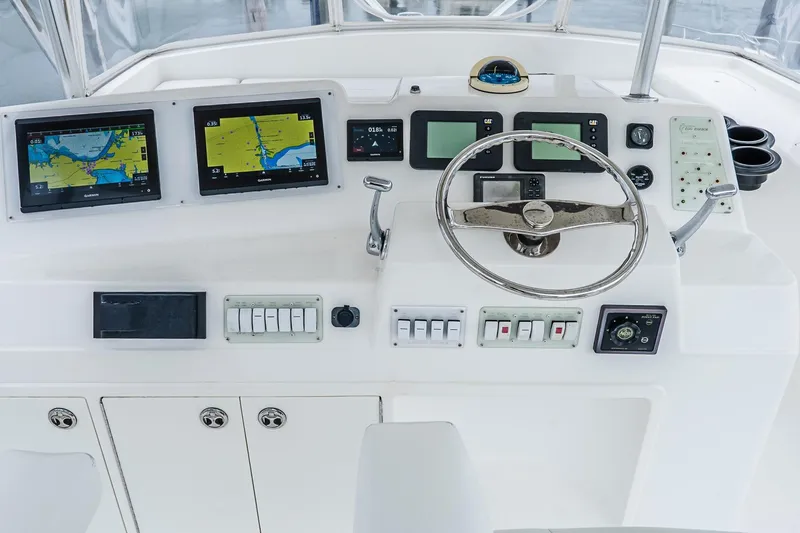 Peeling Drag Yacht Photos Pics Control panel of a 2003 Egg Harbor 42 Convertible yacht with navigation screens and steering wheel.