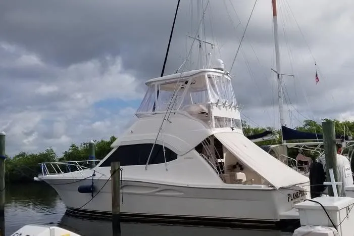 Plane Pirate Yacht Photos Pics 2004 Riviera 37 Convertible yacht docked under cloudy skies.