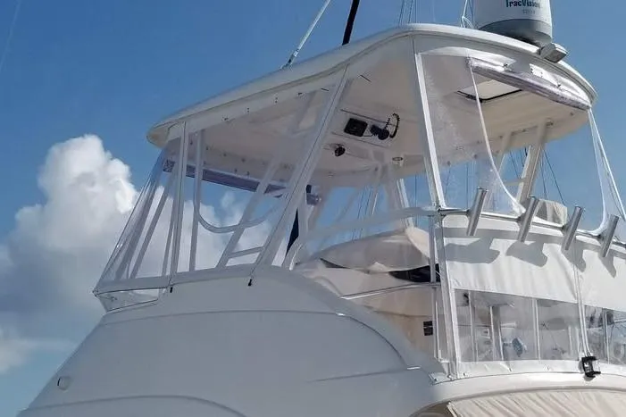 Plane Pirate Yacht Photos Pics 2004 Riviera 37 Convertible yacht with clear enclosure against a blue sky.
