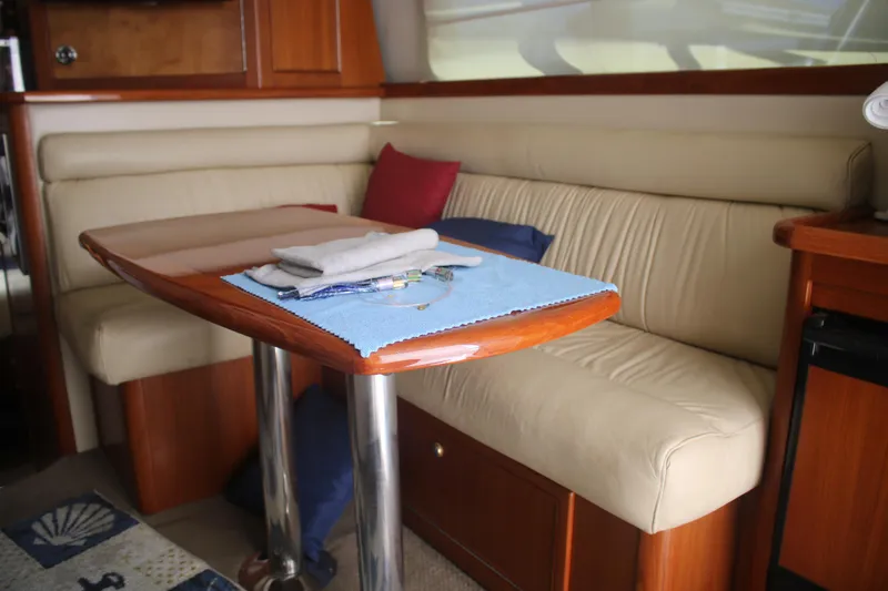 Plane Pirate Yacht Photos Pics Interior of 2004 Riviera 37 Convertible yacht with beige seating and wooden table.