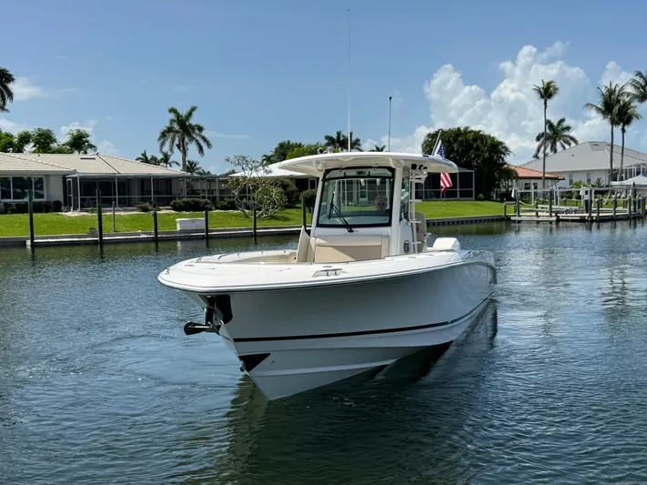  Yacht Photos Pics 2018 Boston Whaler 330 Outrage boat on calm water, surrounded by palm trees.