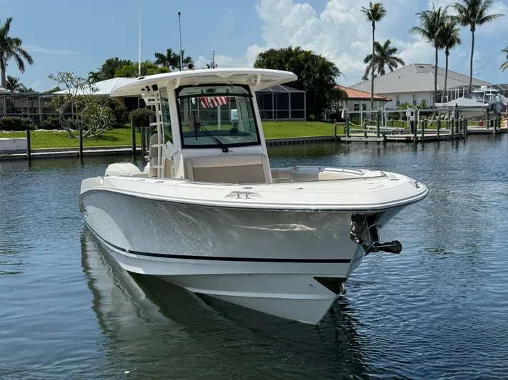  Yacht Photos Pics 2018 Boston Whaler 330 Outrage boat on calm water, surrounded by palm trees.