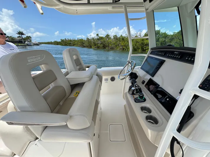  Yacht Photos Pics 2018 Boston Whaler 330 Outrage boat interior with helm and seating, cruising on a scenic waterway.
