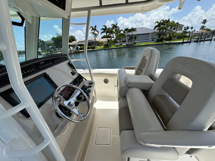  Yacht Photos Pics 2018 Boston Whaler 330 Outrage helm with dual seats, overlooking a scenic waterfront.