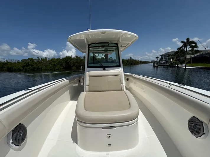  Yacht Photos Pics 2018 Boston Whaler 330 Outrage boat on calm water, clear sky, and lush surroundings.