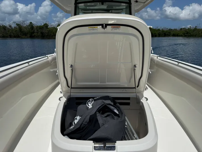  Yacht Photos Pics 2018 Boston Whaler 330 Outrage boat with open storage compartment, docked on a sunny day.