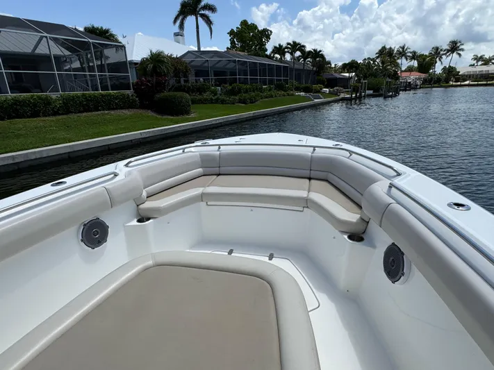  Yacht Photos Pics 2018 Boston Whaler 330 Outrage boat with spacious seating, docked near a scenic waterfront.