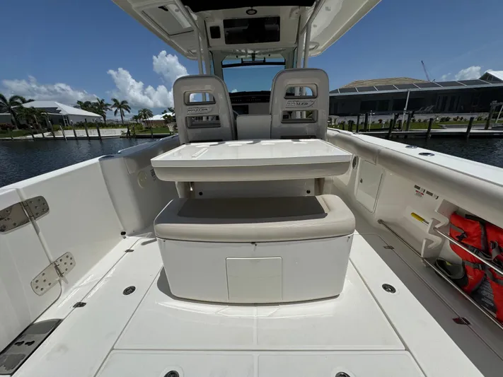  Yacht Photos Pics 2018 Boston Whaler 330 Outrage boat interior with seating and storage, docked by palm trees.