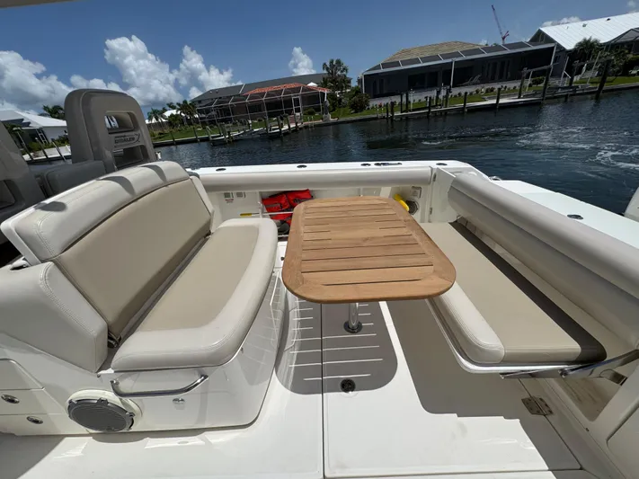  Yacht Photos Pics 2018 Boston Whaler 330 Outrage boat interior with seating and wooden table, dockside view.