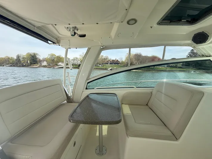  Yacht Photos Pics 2018 Boston Whaler 345 Conquest interior with seating and table, overlooking a scenic waterfront.